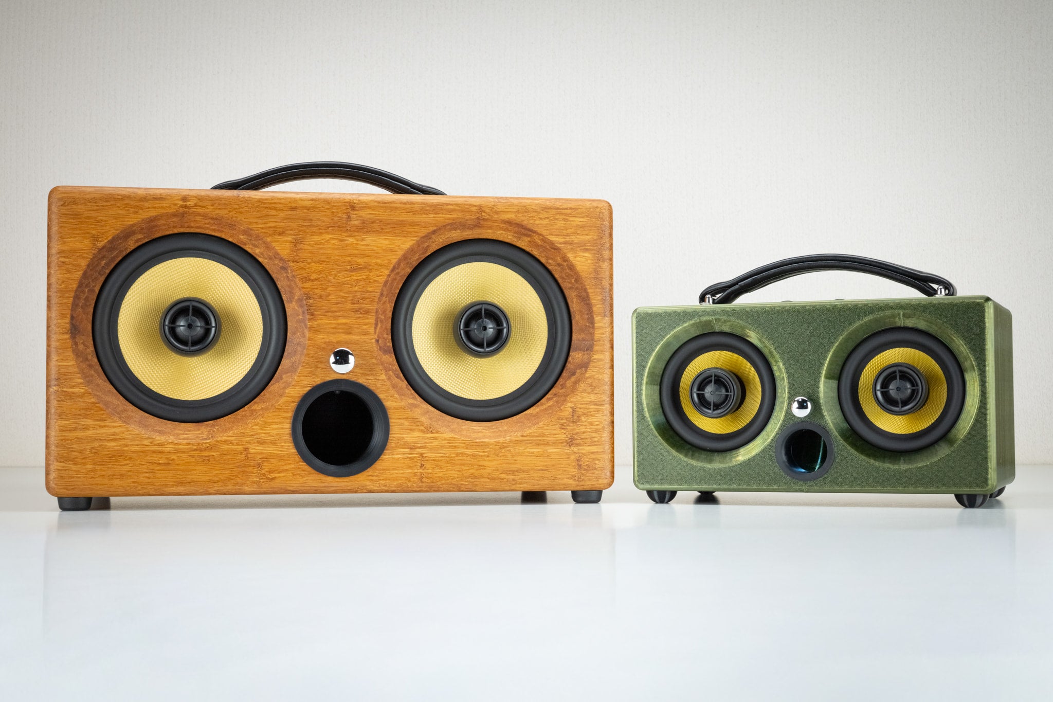 Thodio 3D-printed speaker beside the larger handmade bamboo iBox XC wireless speaker, showing size comparison