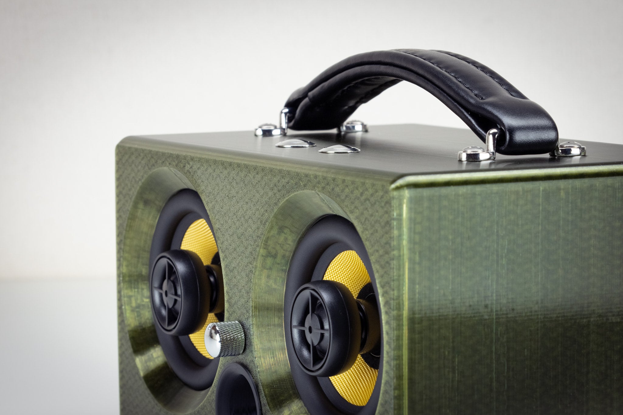 Corner detail of the green Thodio 3D-printed audiophile speaker showing the twin coaxial drivers and volume knob