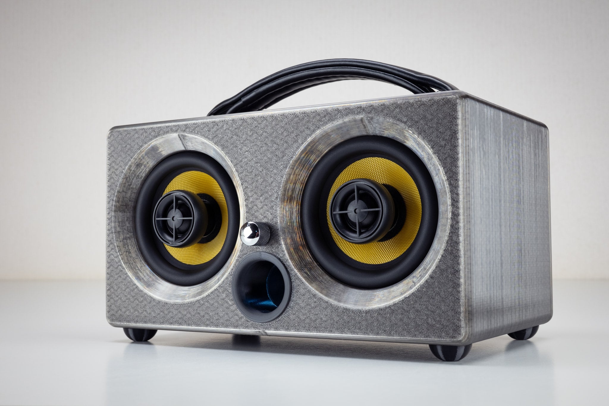 Grey gunmetal Thodio iBox Mini 3D-printed Bluetooth speaker, front three-quarter view with twin coaxial drivers and leather handle