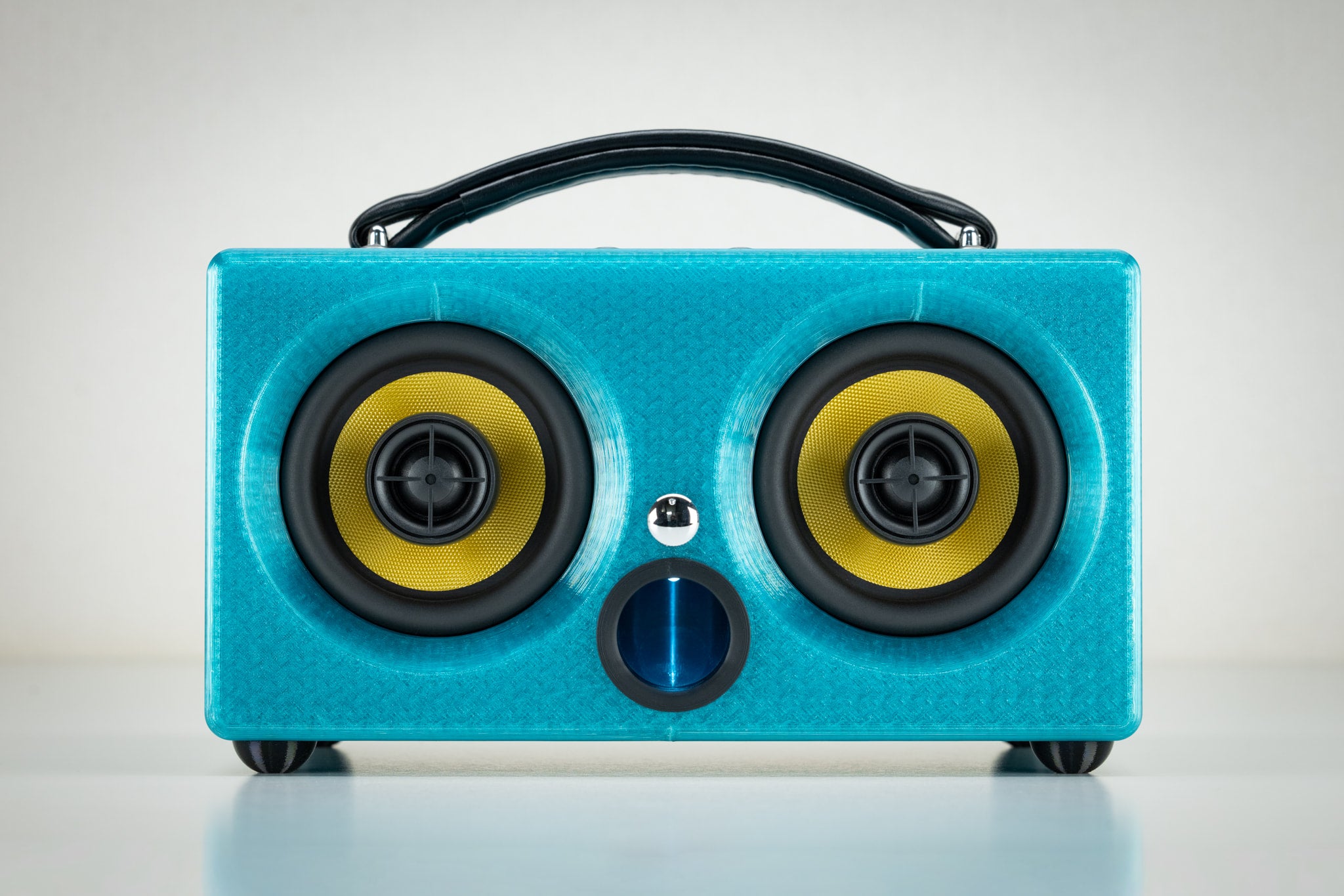 Front view of the turquoise Thodio iBox Mini 3D-printed Bluetooth speaker with twin yellow drivers and central bass port