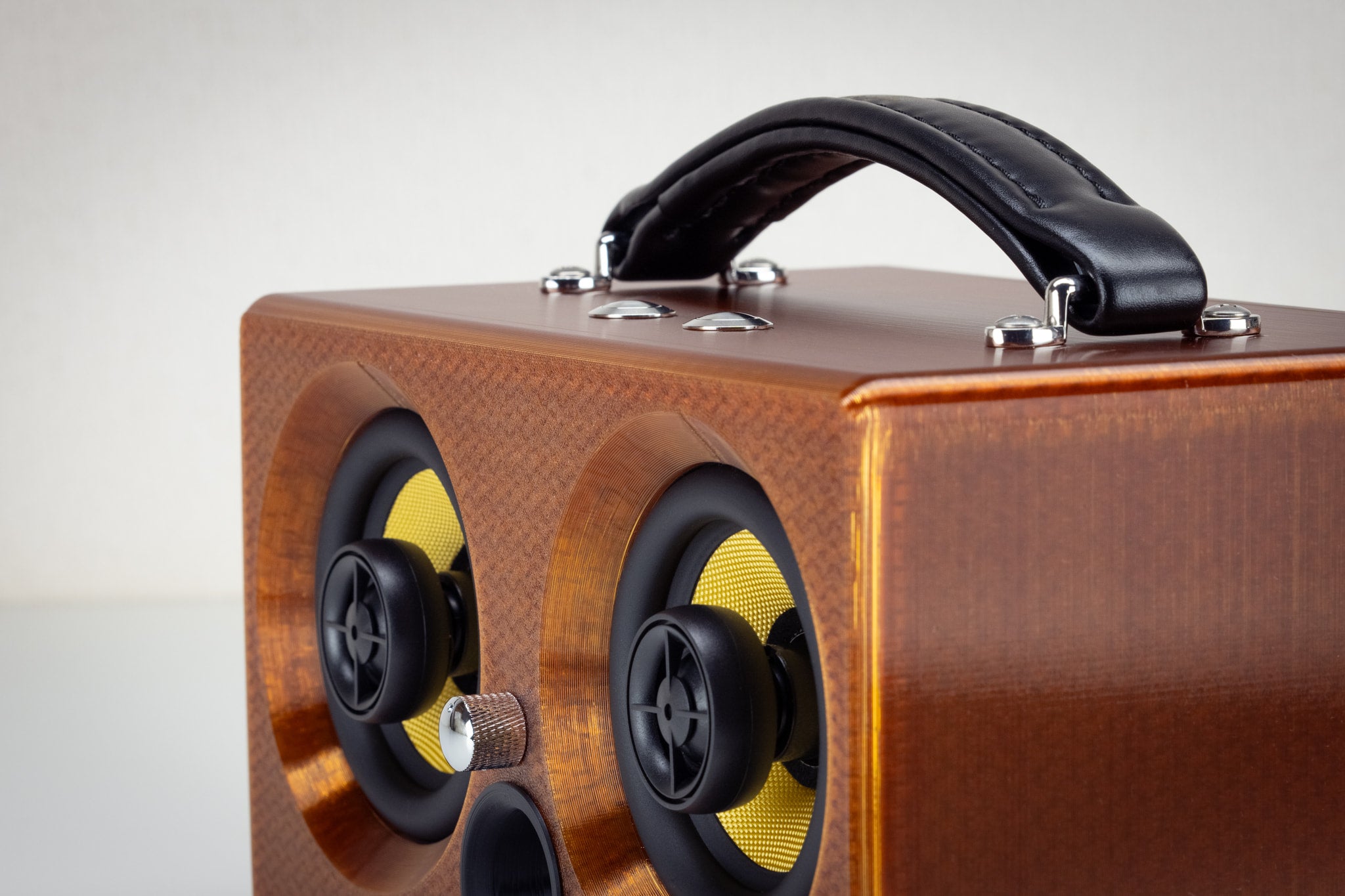 Corner detail of the amber Thodio iBox Mini 3D-printed audiophile speaker showing the twin coaxial drivers and volume knob