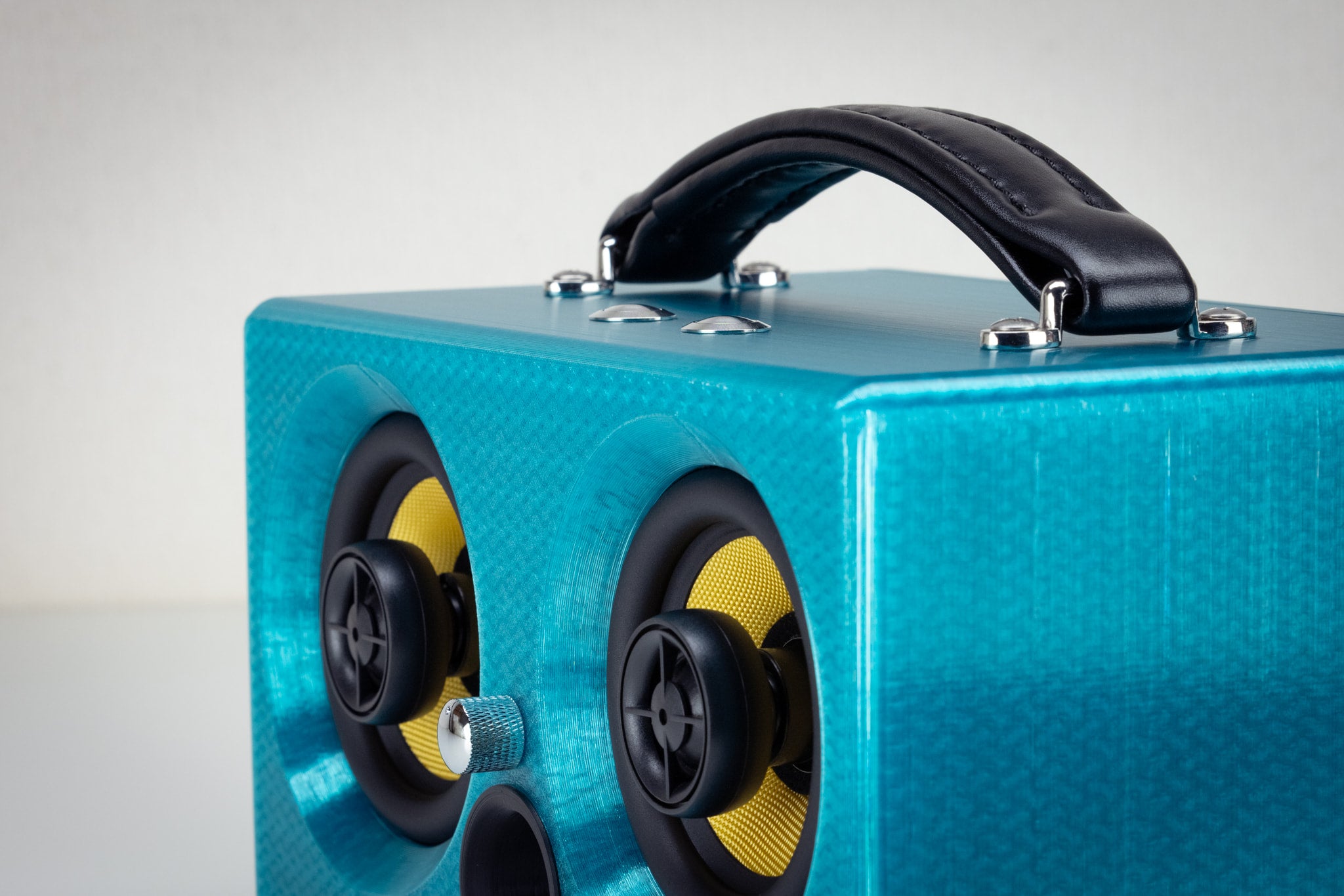 Corner detail of the turquoise Thodio iBox Mini 3D-printed audiophile speaker showing the twin coaxial drivers and volume knob