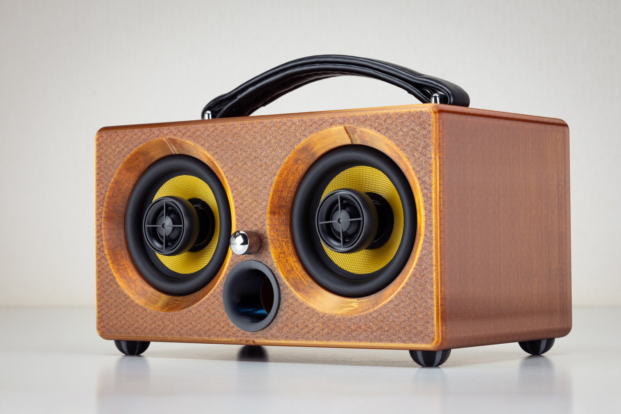 Front view of the amber Thodio iBox Mini 3D-printed Bluetooth speaker with twin yellow drivers and central bass port