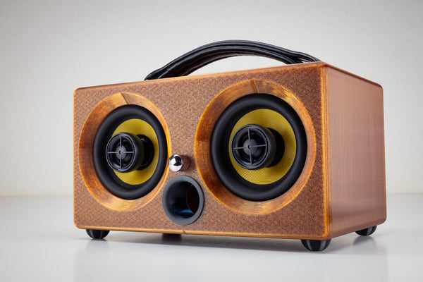 Thodio iBox Mini 3D-printed Bluetooth speaker in amber recycled filament, front three-quarter view with twin coaxial drivers and leather handle