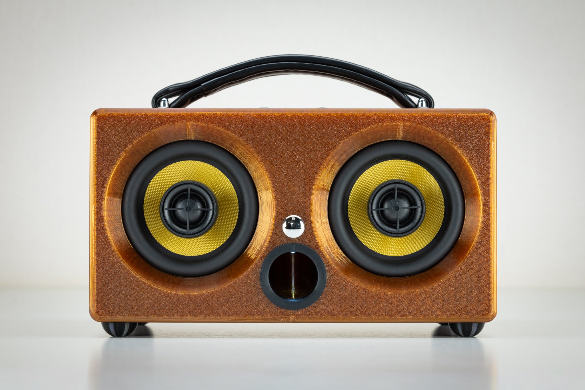 Low-angle view of the portable amber Thodio iBox Mini 3D-printed Bluetooth speaker with front bass-reflex port
