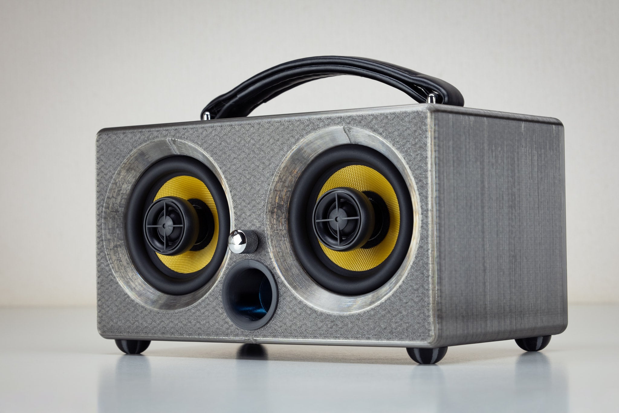 Grey gunmetal Thodio iBox Mini 3D-printed Bluetooth speaker, angled front view with yellow audiophile drivers and bass port