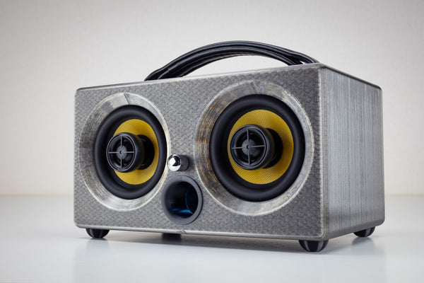Grey gunmetal Thodio iBox Mini 3D-printed Bluetooth speaker, front three-quarter view with twin coaxial drivers and leather handle