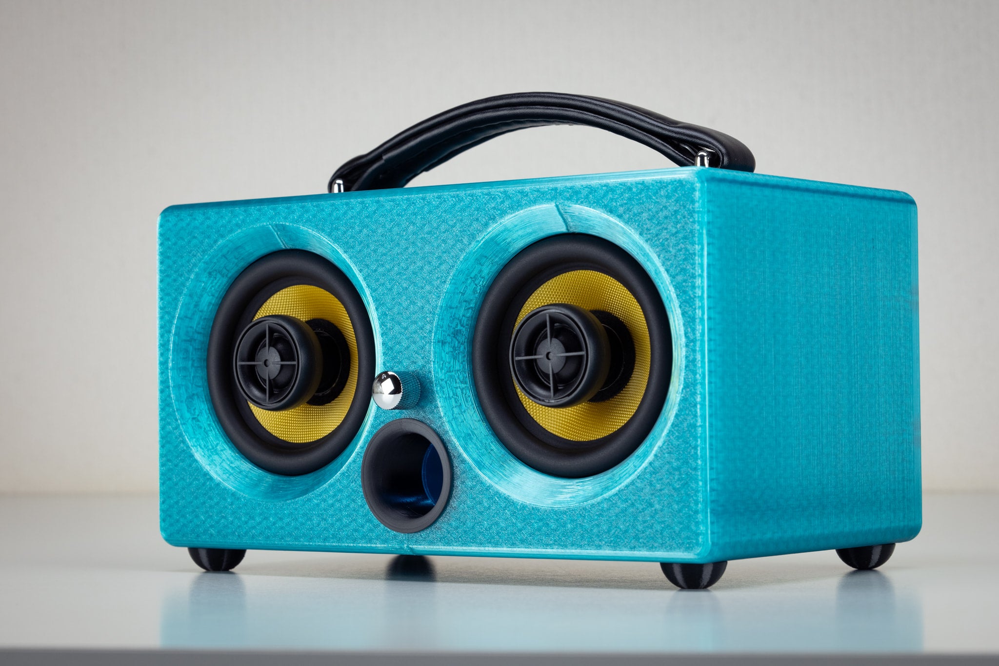 Turquoise Thodio iBox Mini 3D-printed Bluetooth speaker, angled front view with yellow audiophile drivers and bass port