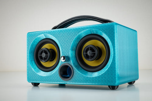 Turquoise Thodio iBox Mini 3D-printed Bluetooth speaker, front three-quarter view with twin coaxial drivers and leather handle