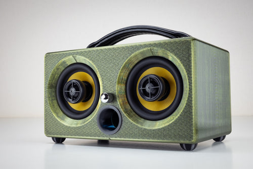 Thodio iBox Mini 3D-printed portable Bluetooth speaker in emerald green, front three-quarter view showing twin coaxial drivers and leather handle