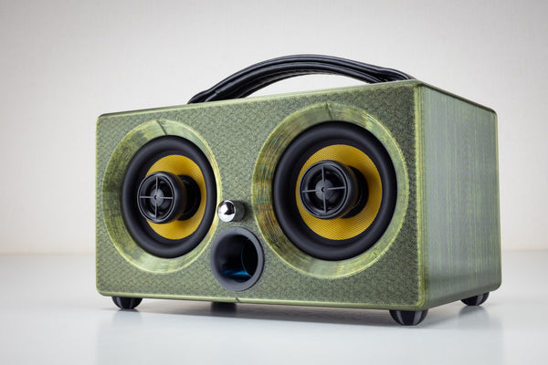Thodio iBox Mini 3D-printed portable Bluetooth speaker in emerald green, front three-quarter view showing twin coaxial drivers and leather handle
