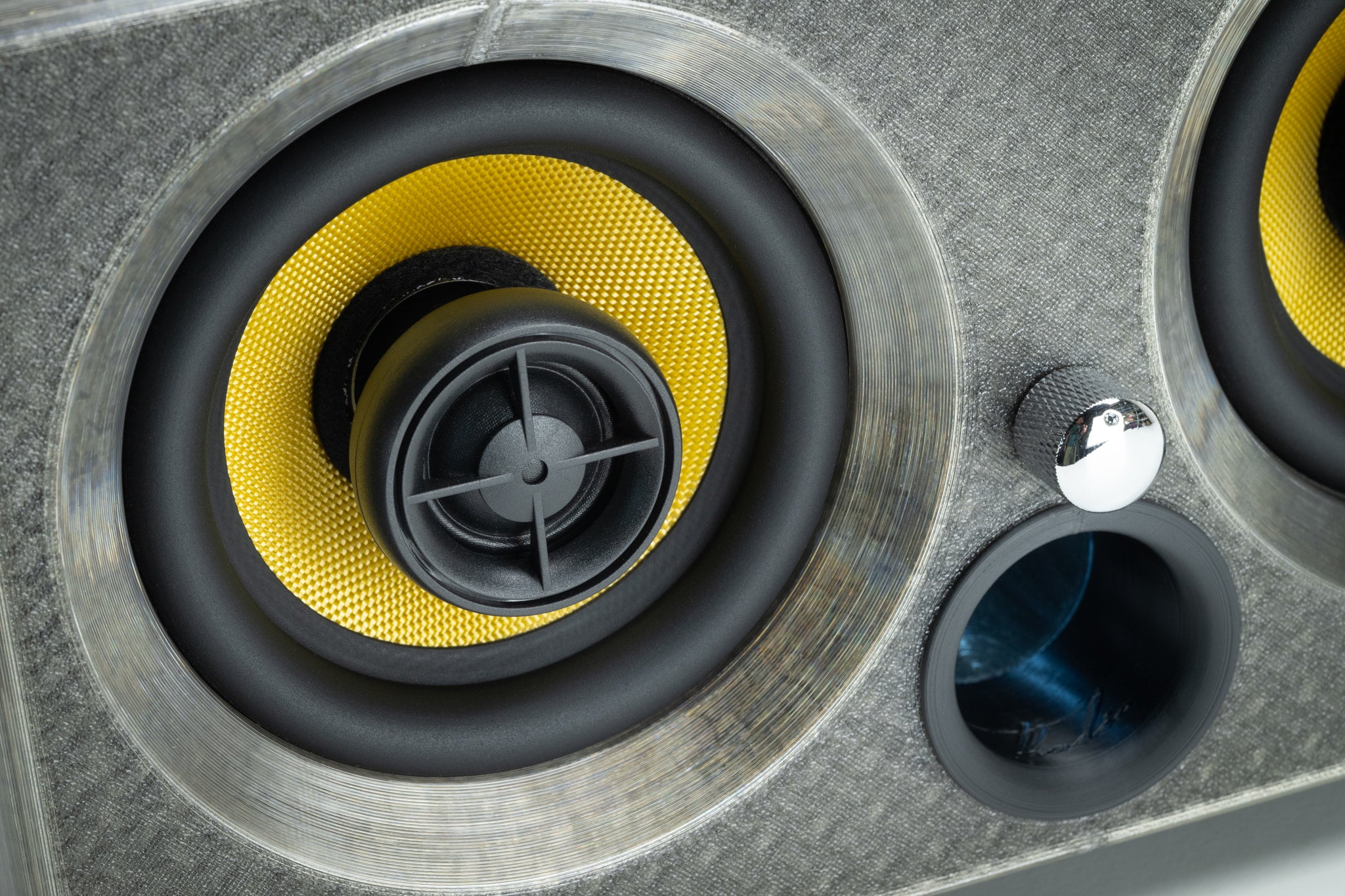 Macro detail of the grey Thodio iBox Mini driver showing the Kevlar coaxial cone, silk-dome tweeter and bass-reflex port